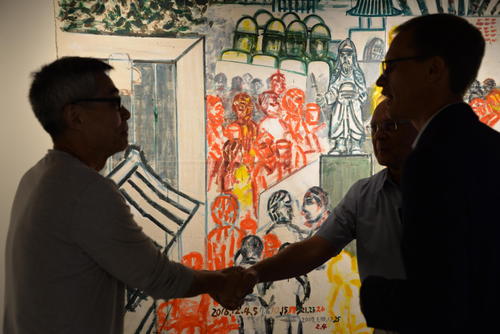 Paul Heidebrecht shaking hands with Heng-Gil Han in the backlit Grebel Gallery