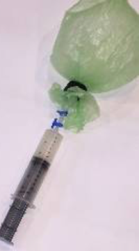 Syringe attached to plastic bag.