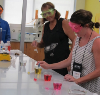 A woman showing a demo with chemistry equipment and coloured liquids 2.