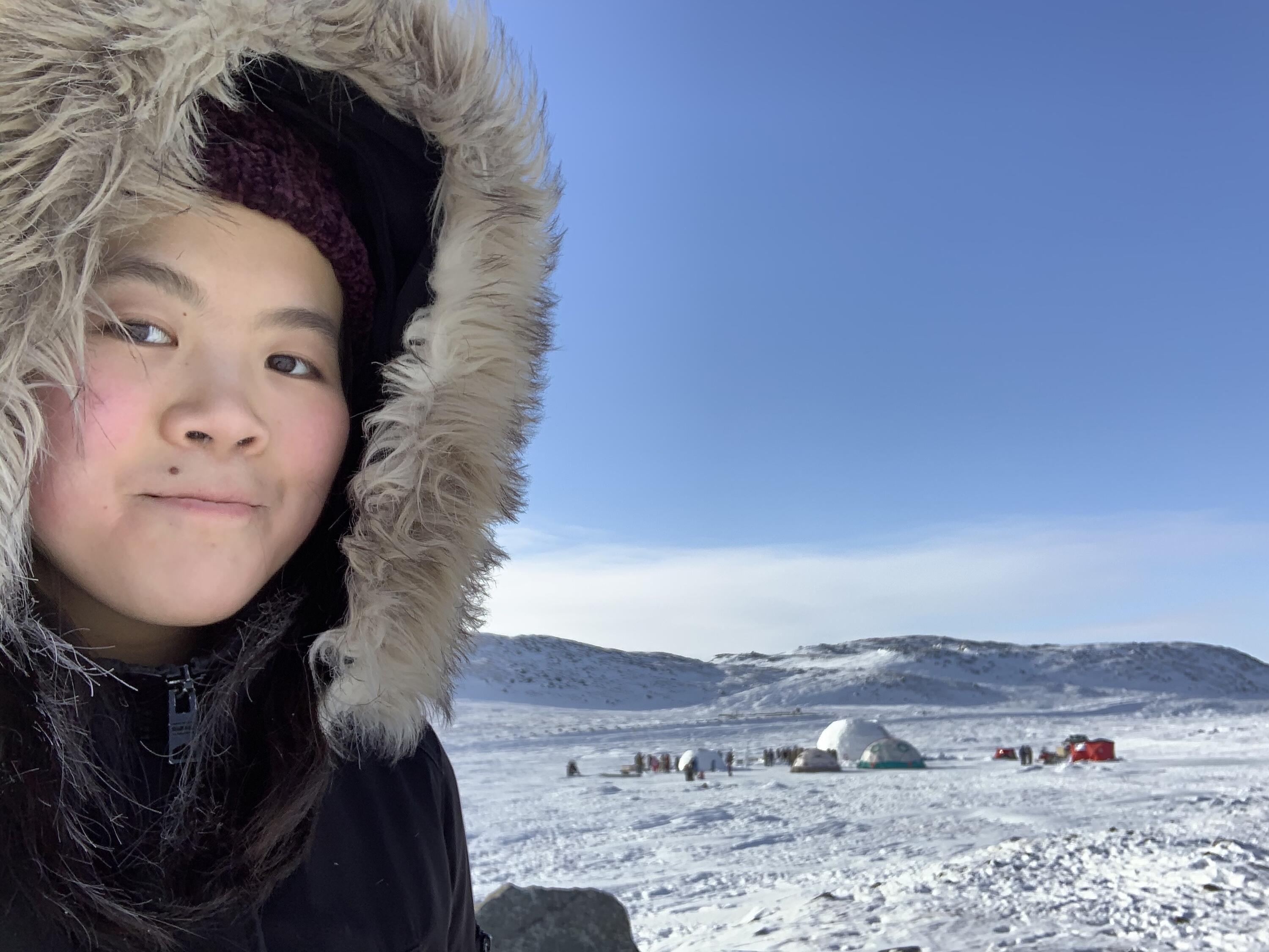 Katie Yu in front of a qaggiq (large communal igloo) near Iqaluit, NU