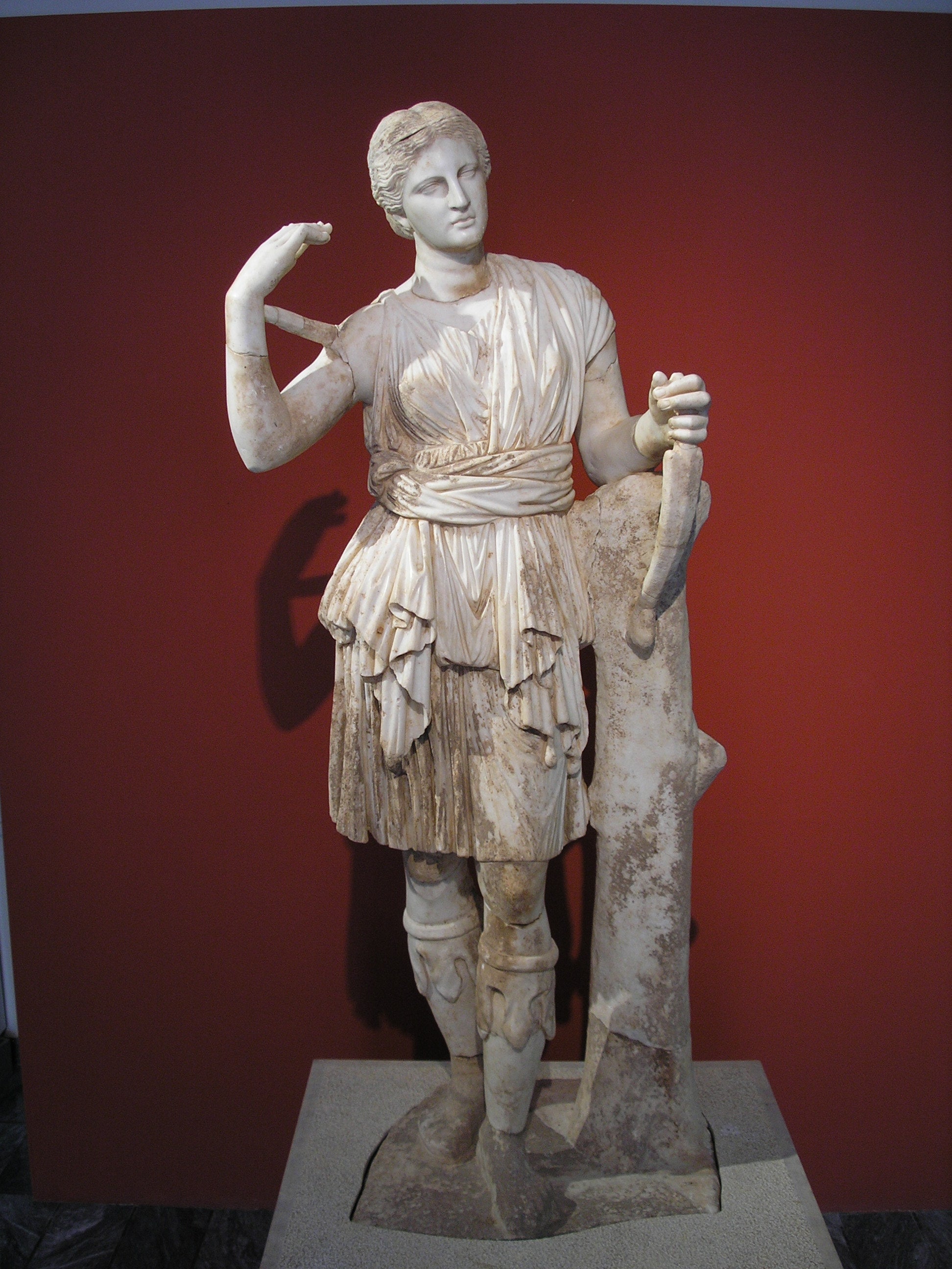 A classical marble sculpture of women in a short, Roman-style dress carrying a dagger