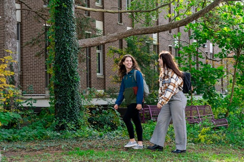 Two students laughing and walking outside Envrionment building 