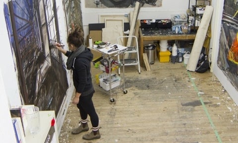 View from above of an artist's studio with the artist working on a painting