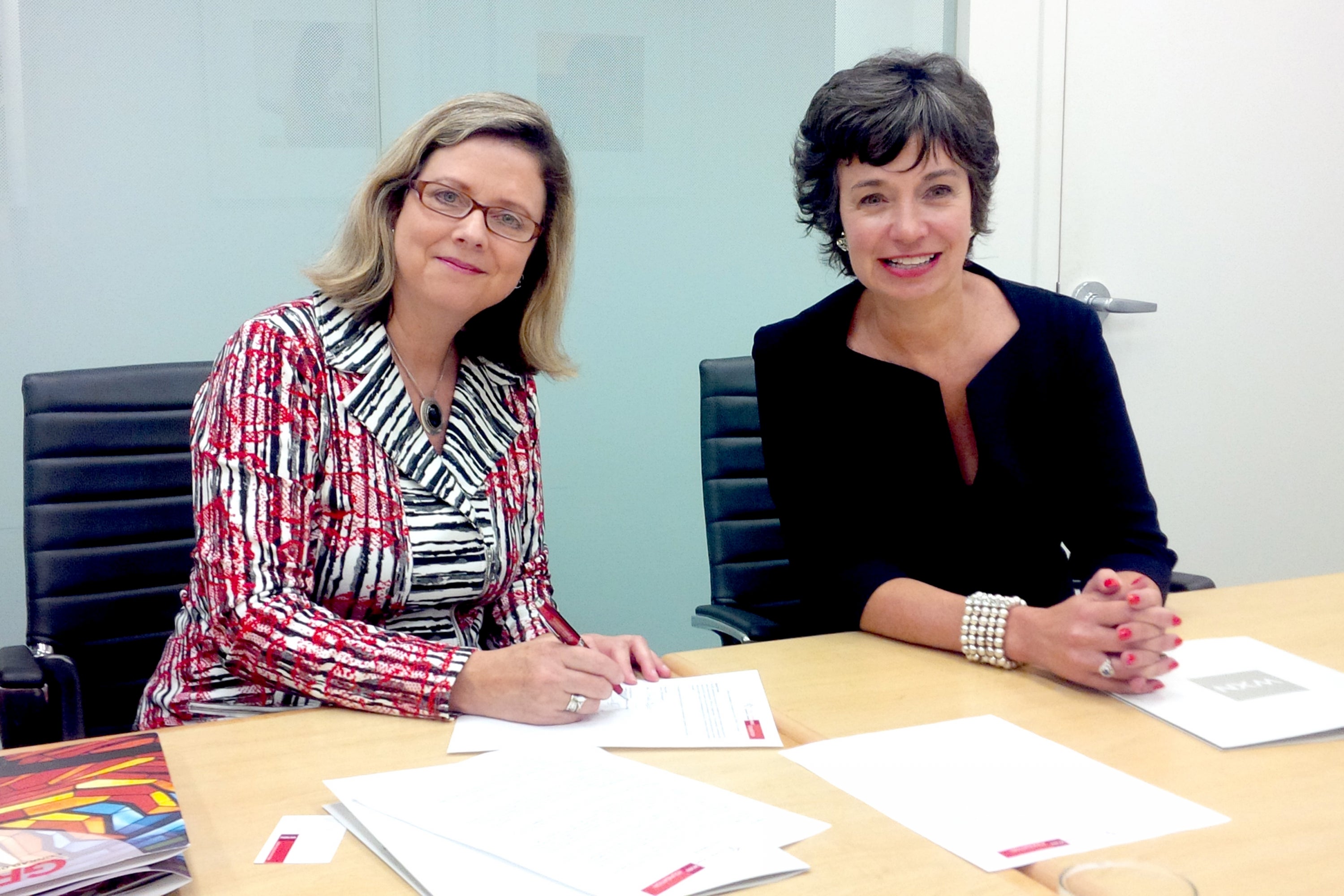 Susan Schultz Huxman and Women’s Executive Network  Founder Pamela Jeffery sign papers for the new MPACS award.