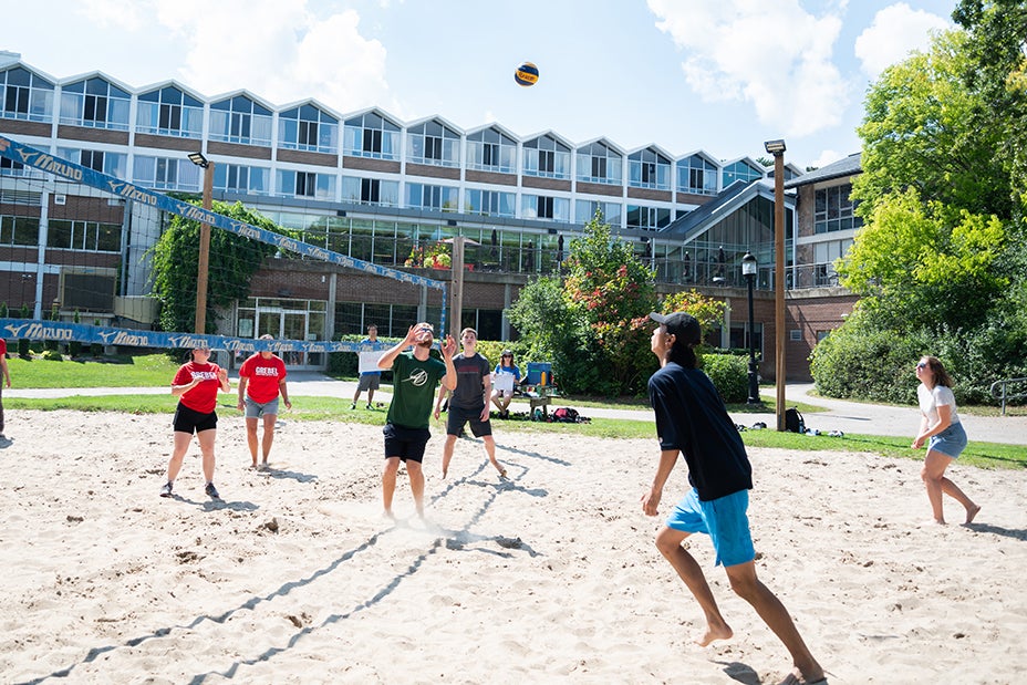 A group of students play volleyball together on the court outside of the Grebel residence in early September on a bright sunny day.