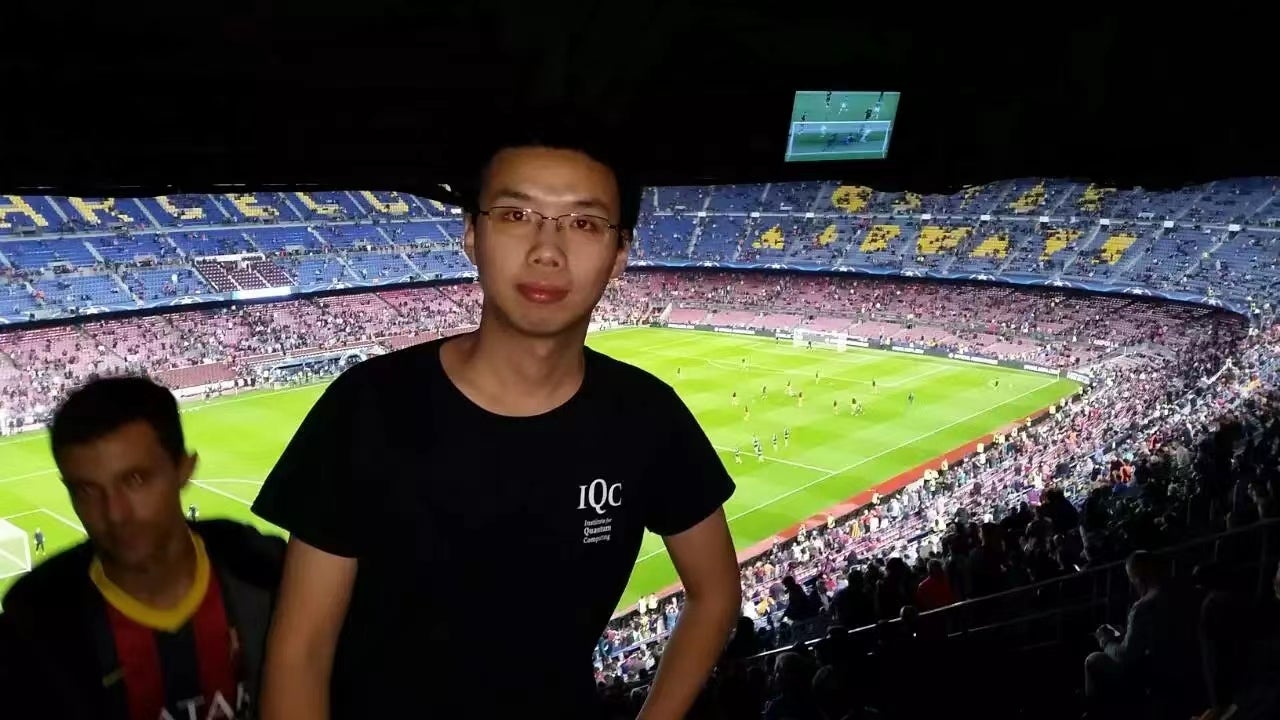 Dawei Lu at a soccer stadium wearing an IQC t-shirt