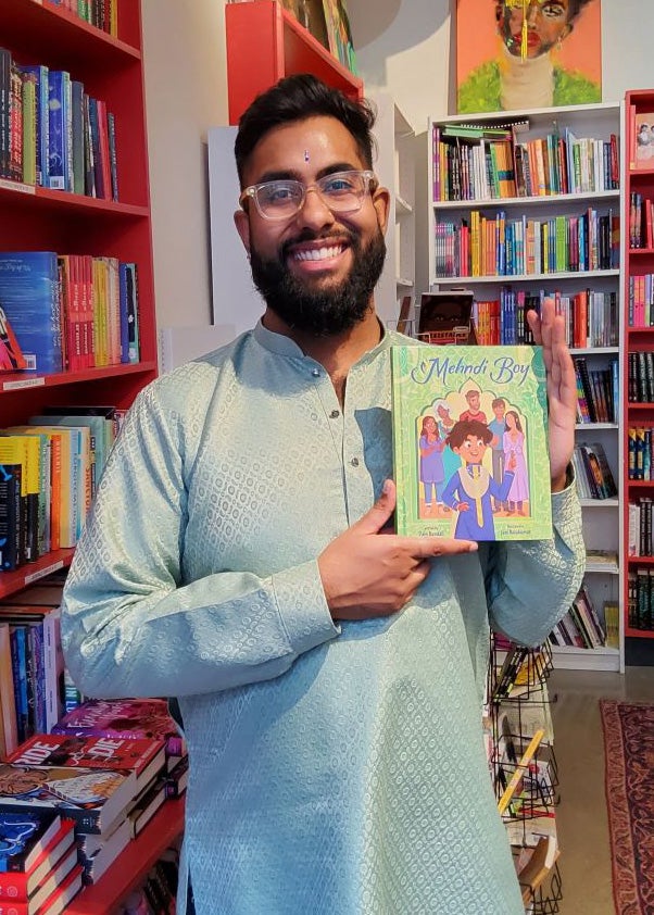 Zain Bandali smiling and holding up his book, Mehndi Boy