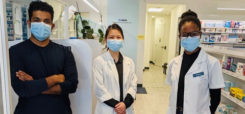 Three pharmacists wearing masks and standing in the pharmacy