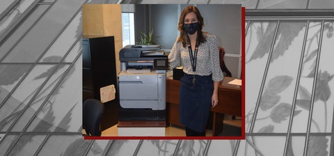 Kaitlin wearing a mask and standing next to a printer