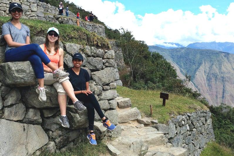 Three students sitting on a clifftop in Peru