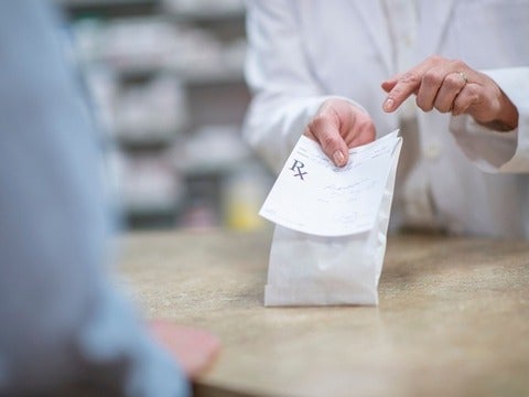 Hands holding and pointing to a prescription bag