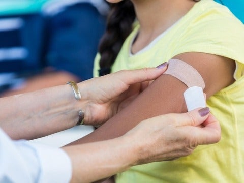 A bandaid being placed on a woman's arm