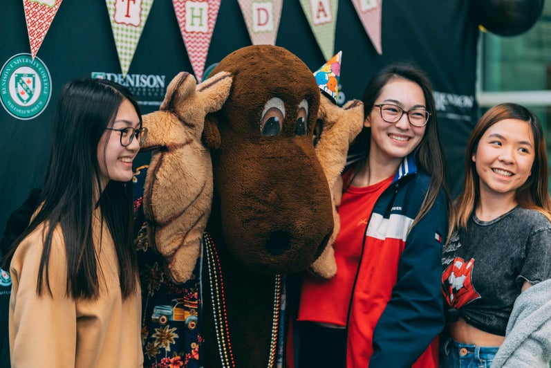 students smiling with renison moose mascot