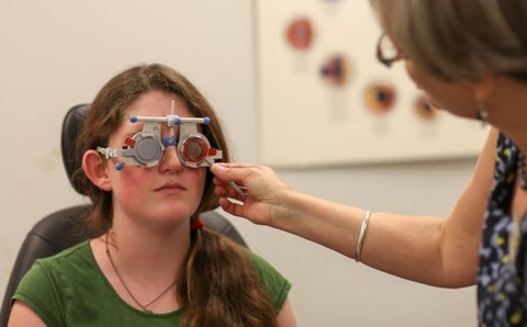 Client wearing a trial lens frames while optometrist trials lenses to determine prescription.