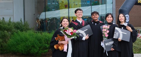 Graduates smiling with degrees in hand