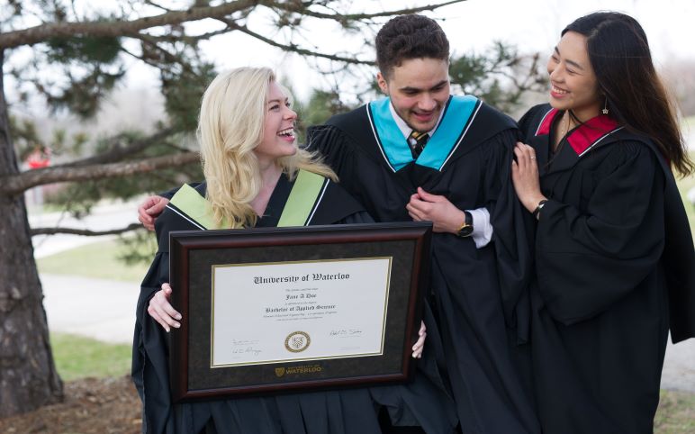 Grads smiling with framed diploma